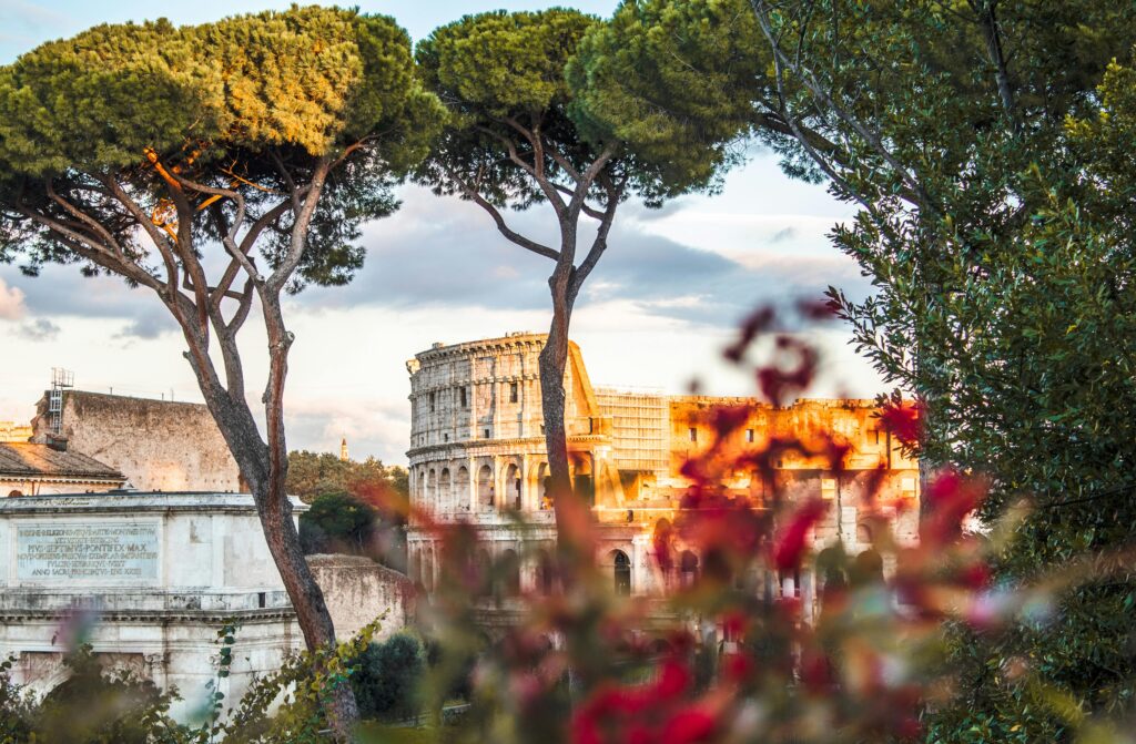 Beautiful view of the Colosseum framed by trees and flowers in Rome, Italy.